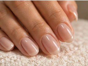Short, rounded nails in a glossy milky pink gel, resting on a soft cream towel