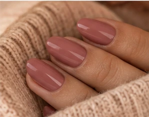 Oval nails in a glossy dusty rose gel, against a soft knit sweater
